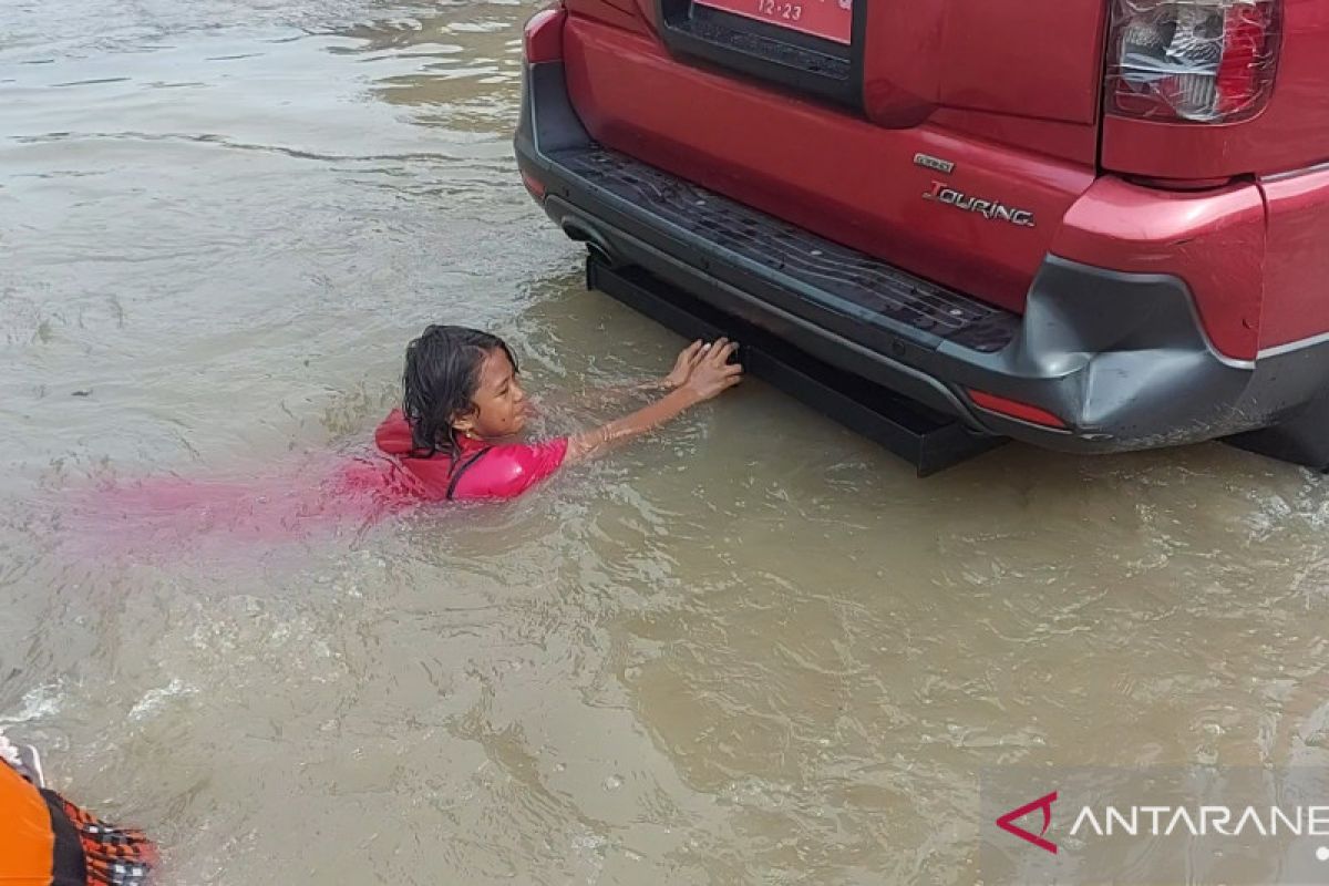 Anak-anak manfaatkan air banjirjadi tempat bermain