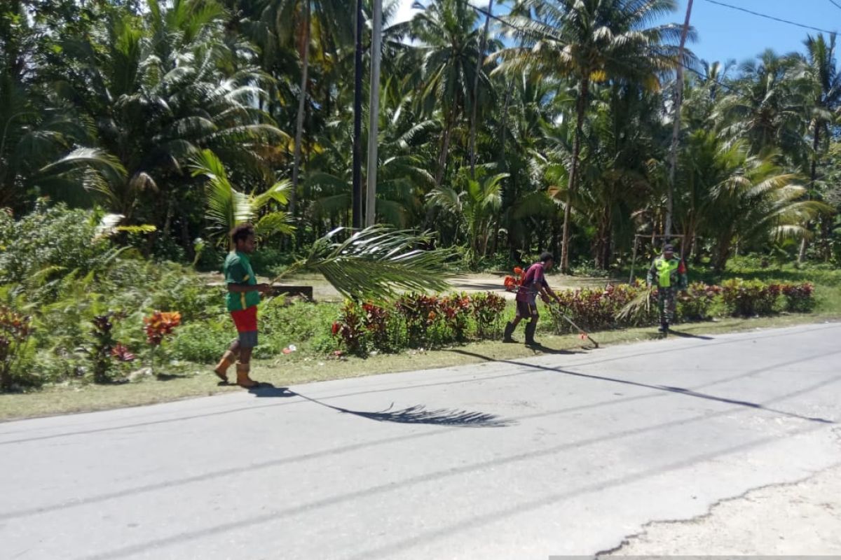 Babinsa gotong royong bersama warga bersihkan rumput di bahu jalan