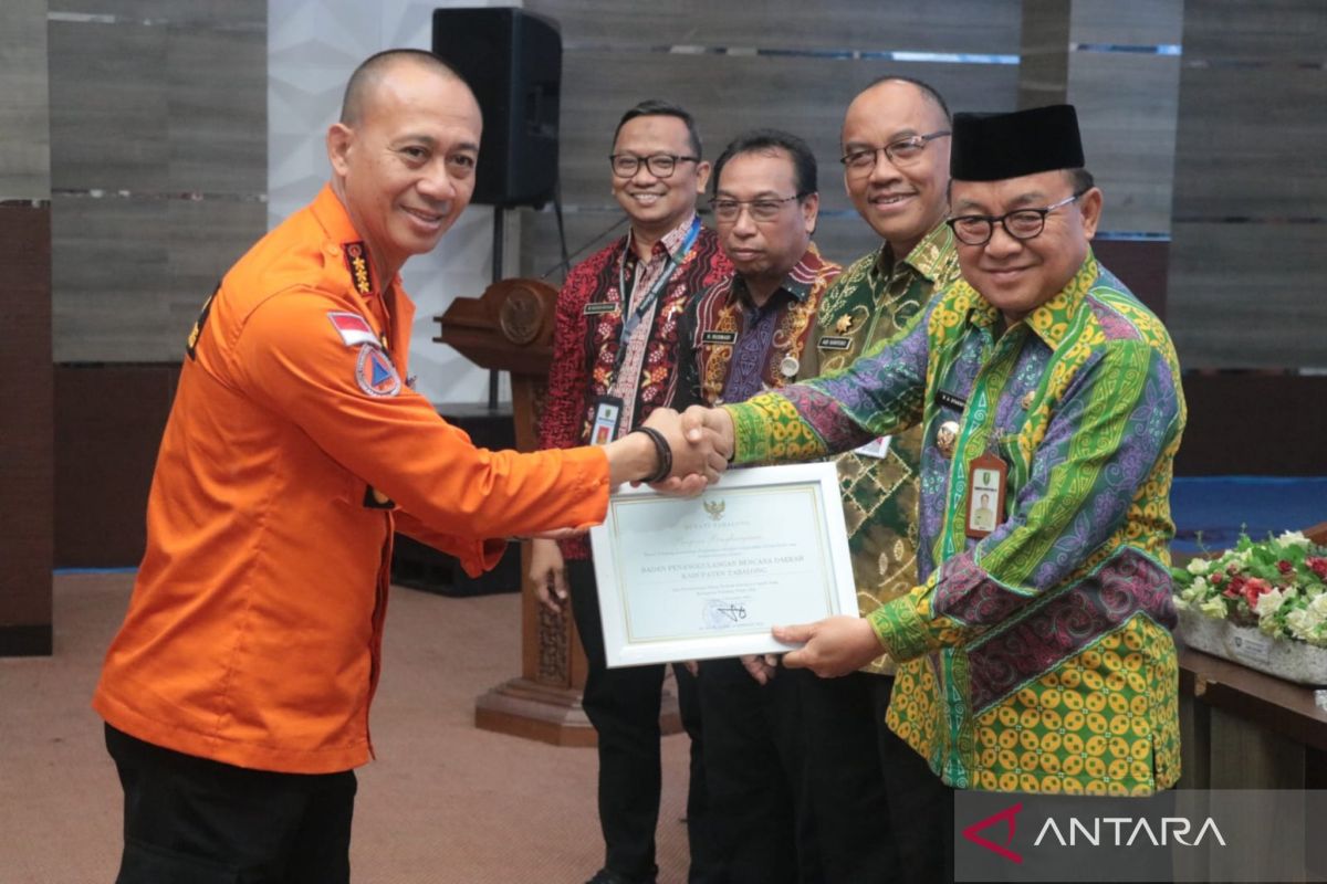 Kepala Pelaksana Badan Penanggulangan Bencana Daerah Kabupaten Tabalong Haris Fakhrozi menerima piagam penghargaan dari Bupati Tabalong H Anang Syakhfiani pada acara penguatan gugus tugas Kota Layak Anak, Kamis (2/11). (ANTARA/HO-Pemkab Tabalong)