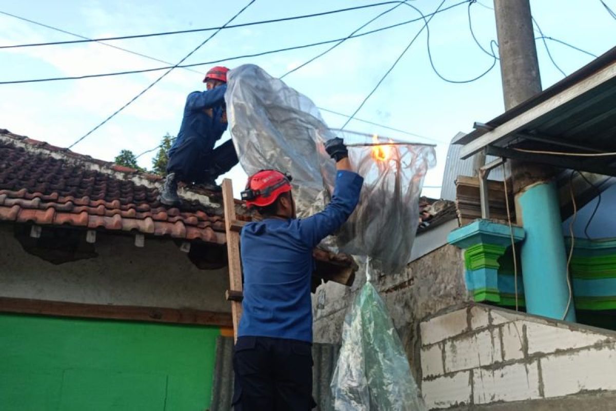 Apar petugas damkar jinakan kobaran api balon udara di atap rumah warga