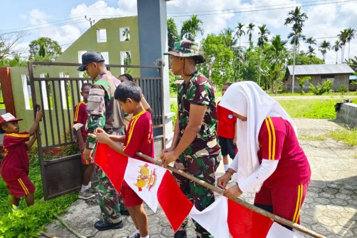 Satgas Yonif 122/TS bersama siswa SD Keerom pasang bendera Merah Putih