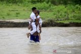 SISWA DAN GURU MENYEBERANGI SUNGAI UNTUK BELAJAR MENGAJAR