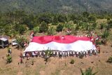 Polisi dan eks napiter membentangkan bendera Merah Putih di Gunung Poso