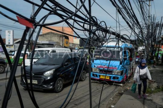 Warga berjalan di bawah kabel utilitas yang semrawut