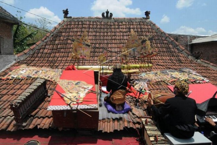 Pertunjukan wayang kulit di atas genteng rumah