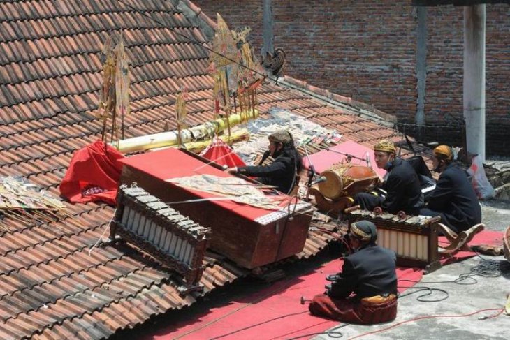 Pertunjukan wayang kulit di atas genteng rumah