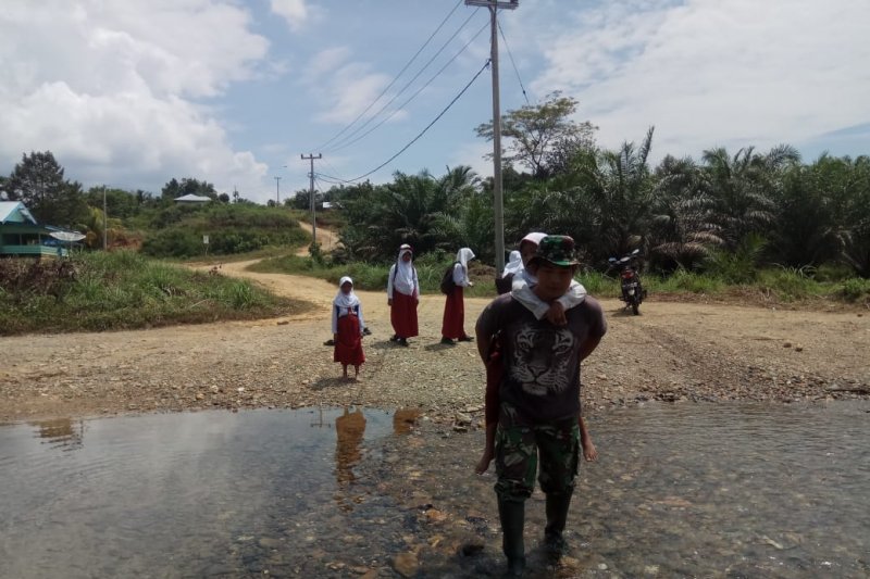 Prajurit TNI ini gendong anak sekolah menyebrangi Sungai