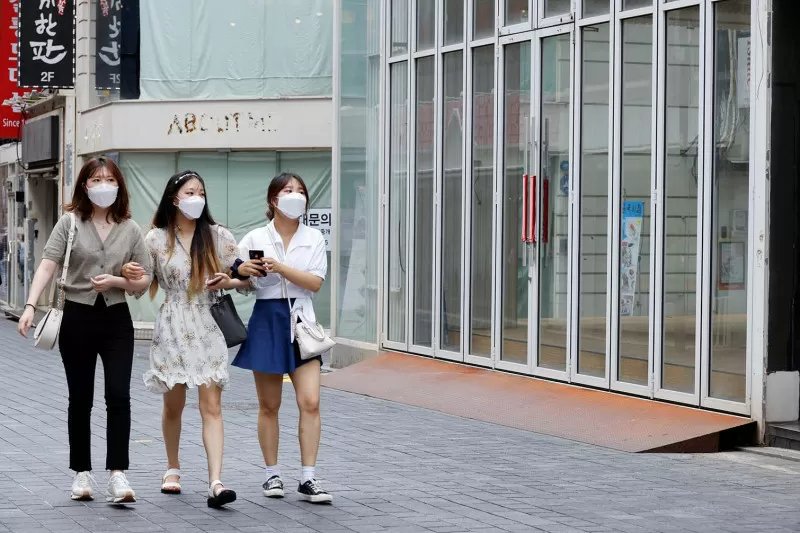 Para wanita mengenakan masker berjalan di distrik perbelanjaan di tengah pandemi penyakit virus corona (COVID-19) di Seoul, Korea Selatan, Jumat (9/7/2021)